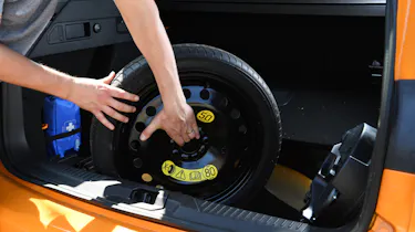 Person lifting a spare wheel out of a car's boot
