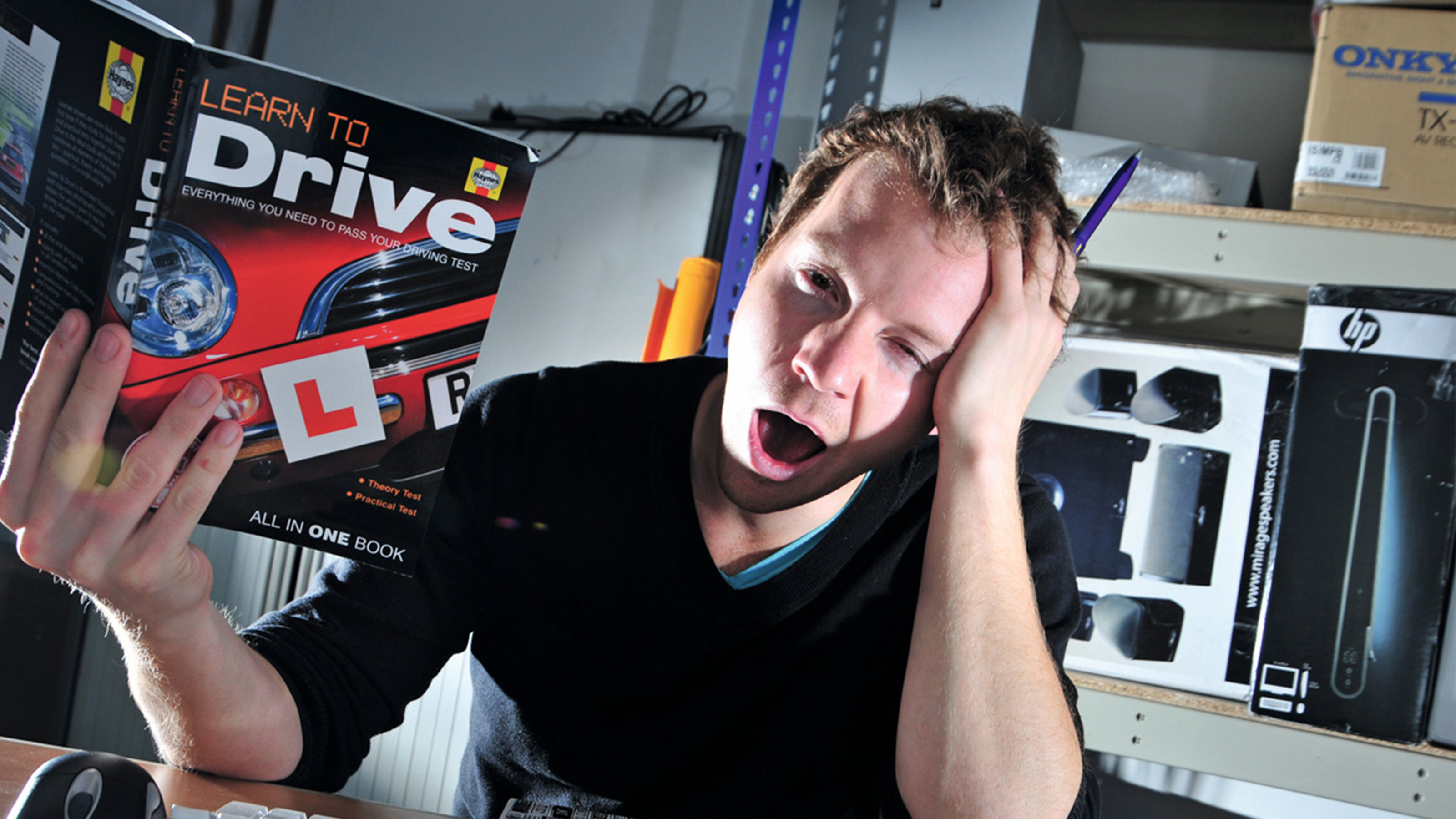 Tired man studying from driving theory test book