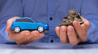 Hands holding a model car and a stack of coins