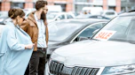 Two people browsing a car dealership forecourt