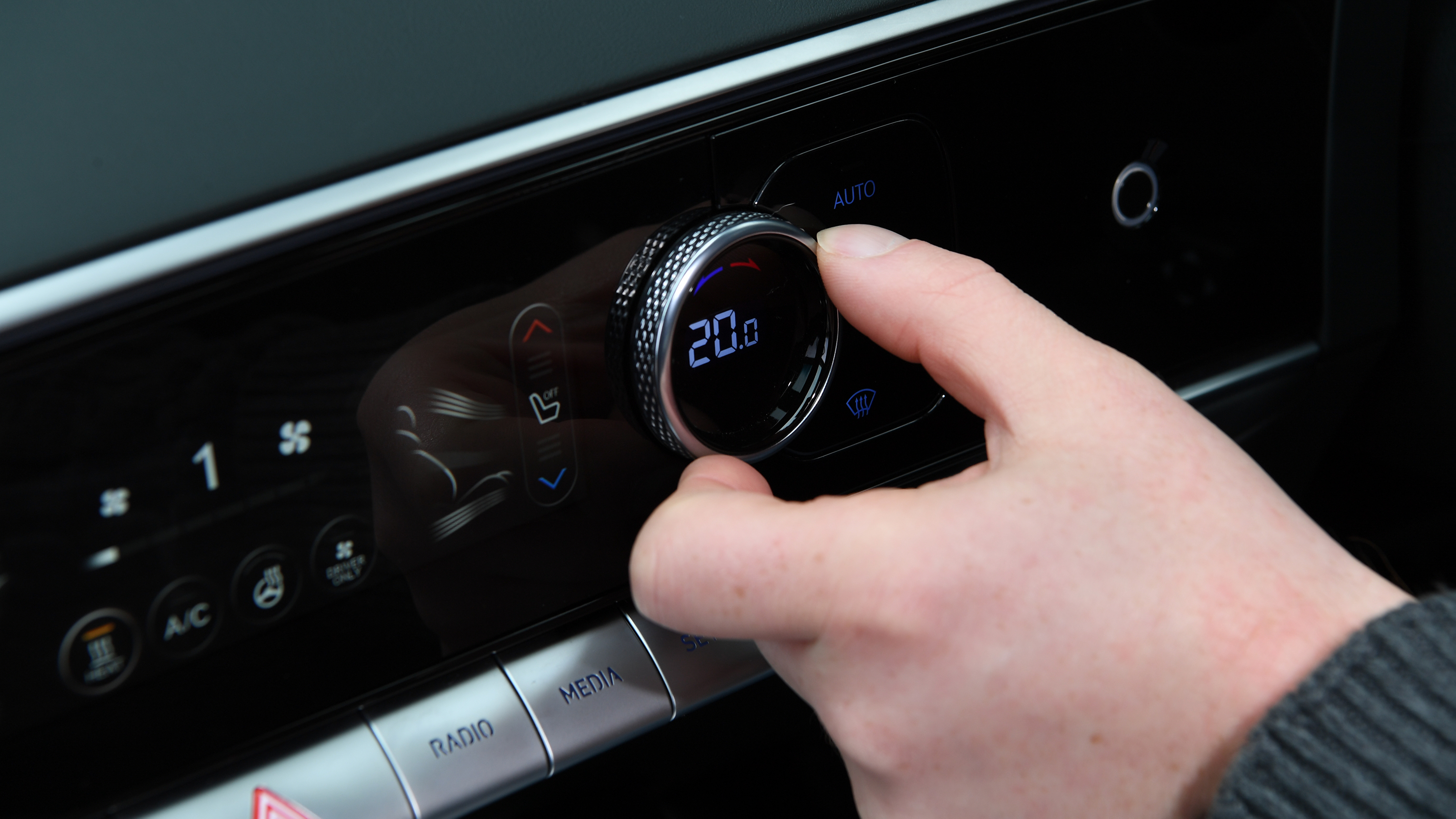 Auto Express chief reviewer Alex Ingram operating Genesis Electrified GV70's climate controls