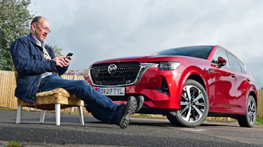 Auto Express chief sub-editor Andy Pringle sitting reading his phone in front of Mazda CX-60