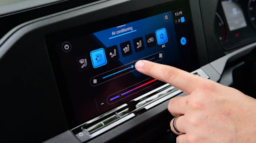 Auto Express senior test editor Dean Gibson standing between operating the Volkswagen Caddy's infotainment system