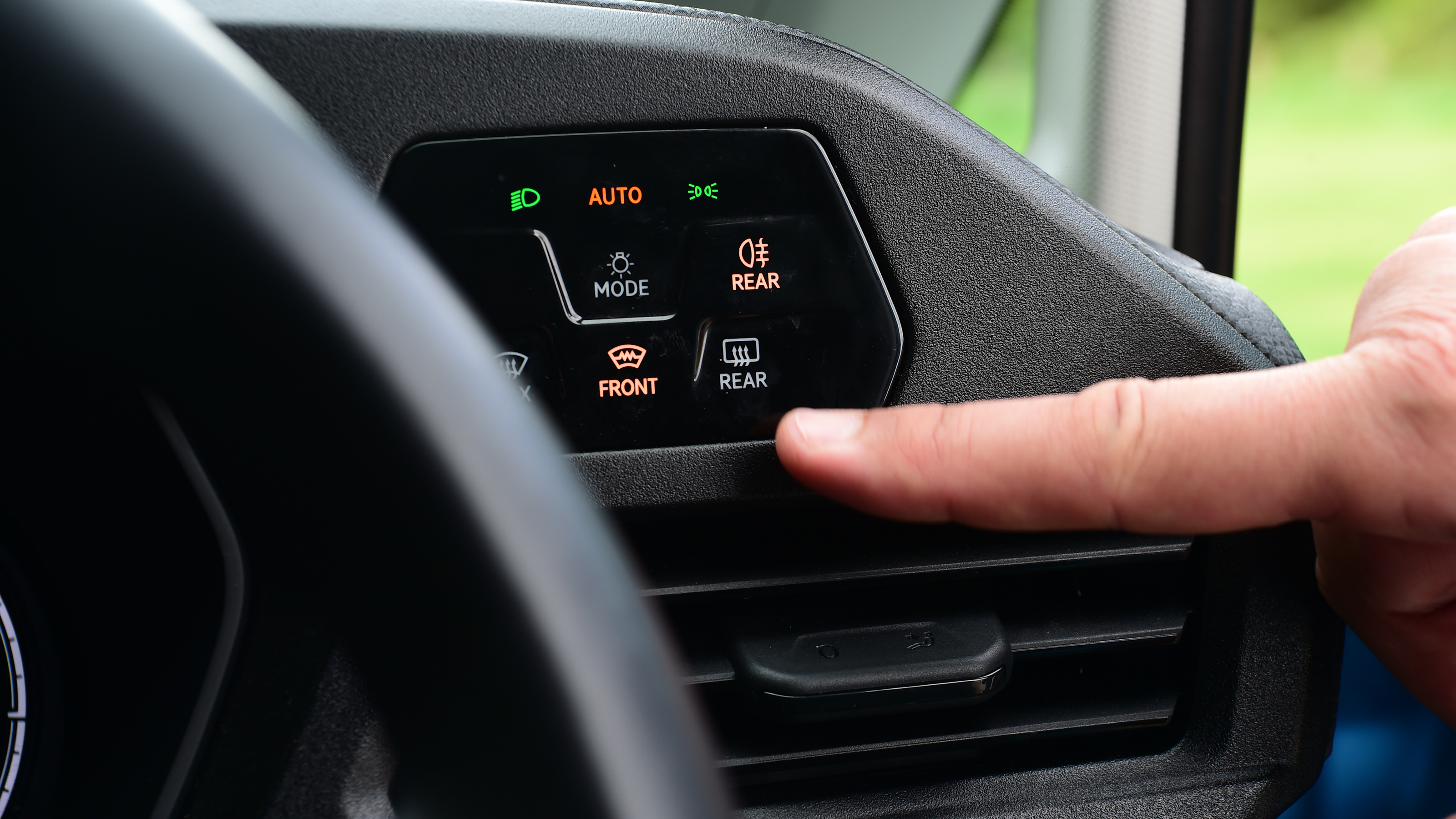 Auto Express senior test editor Dean Gibson standing between operating the Volkswagen Caddy's headlight controls