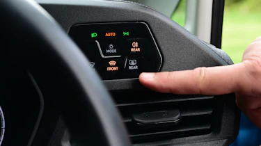Auto Express senior test editor Dean Gibson standing between operating the Volkswagen Caddy's headlight controls