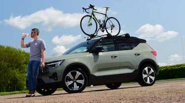 Driving Electric & Carbuyer editor Richard Ingram drinking next to the Volvo XC40