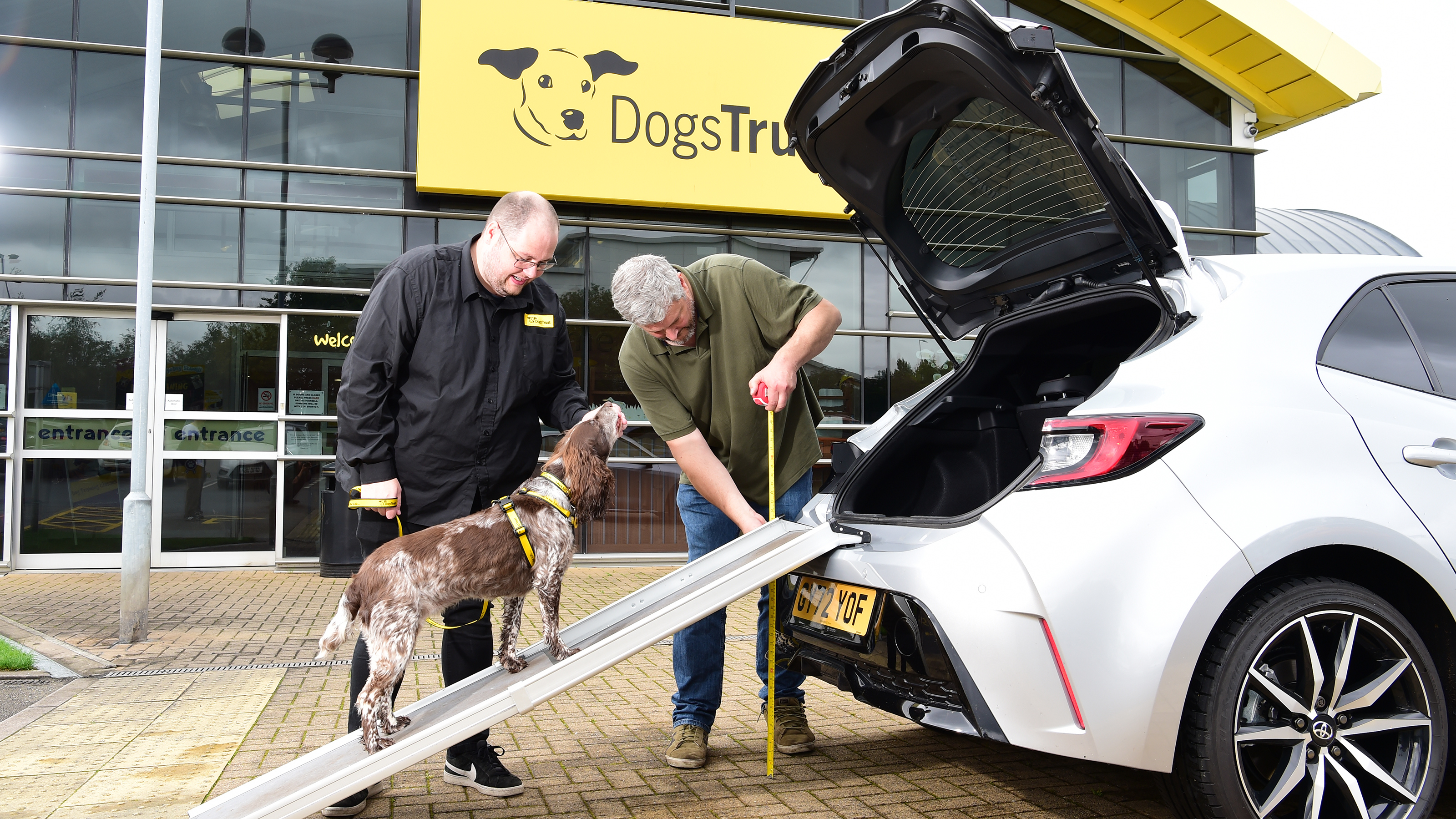 Auto Express current affairs and features editor Chris Rosamond and a Dogs Trust volunteer loading a dog into a Toyota Corolla's boot via a ramp