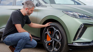 Carbuyer and DrivingElectric editor Richard Ingram inspecting the MG4 XPower's front offside wheel