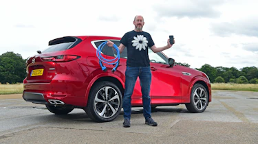 Auto Express chief sub-editor Andy Pringle standing in front of the Mazda CX-60 and holding a charging cable