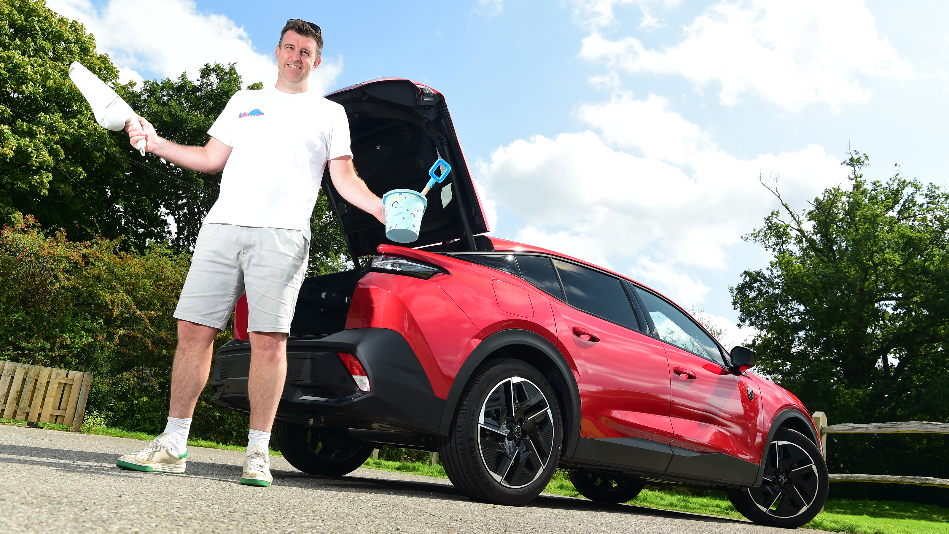 Auto Express group web editor Steve Walker standing by our long term Peugeot 408 GT while holding a bucket and hand-held vacuum cleaner
