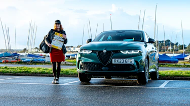 Auto Express pictures editor Dawn Grant standing next to the Alfa Romeo Tonale PHEV while holding a road atlas