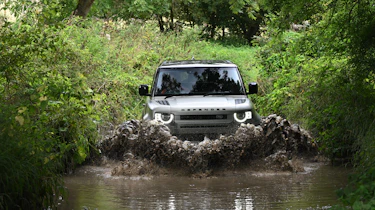 Land Rover Defender driving through a ford
