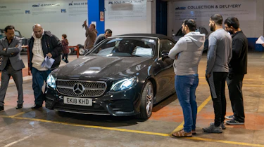 Auction bidders inspecting a Mercedes E-Class Cabriolet