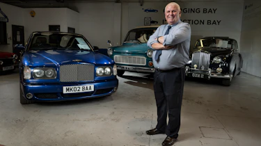 Jim Ronan standing with three classic cars