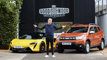Auto Express chief reviewer Alex Ingram standing in front of the Dacia Duster and McLaren Artura outside Goodwood circuit