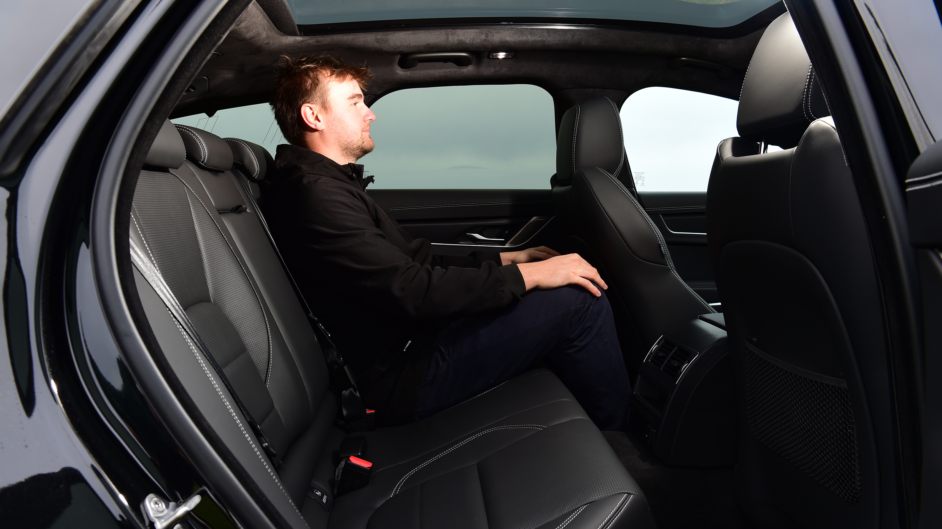 Auto Express senior news reporter Alastair Crooks sitting in the back of the Jaguar XF Sportbrake