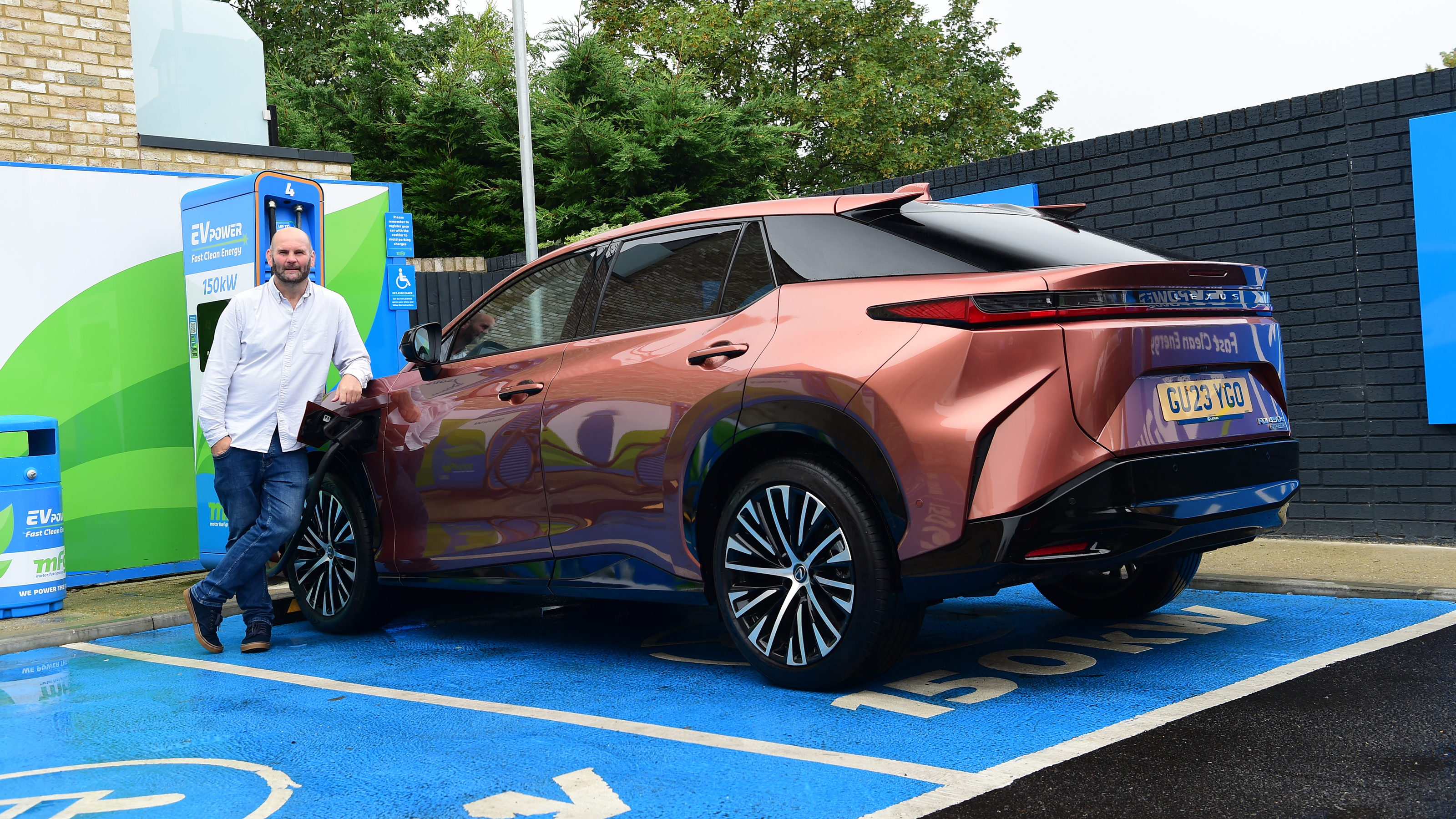 Auto Express creative director Darren Wilson standing with the Lexus RZ in a charging bay