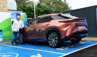Auto Express creative director Darren Wilson standing with the Lexus RZ in a charging bay