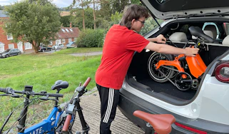 Person loading a folding e-bike into a car boot