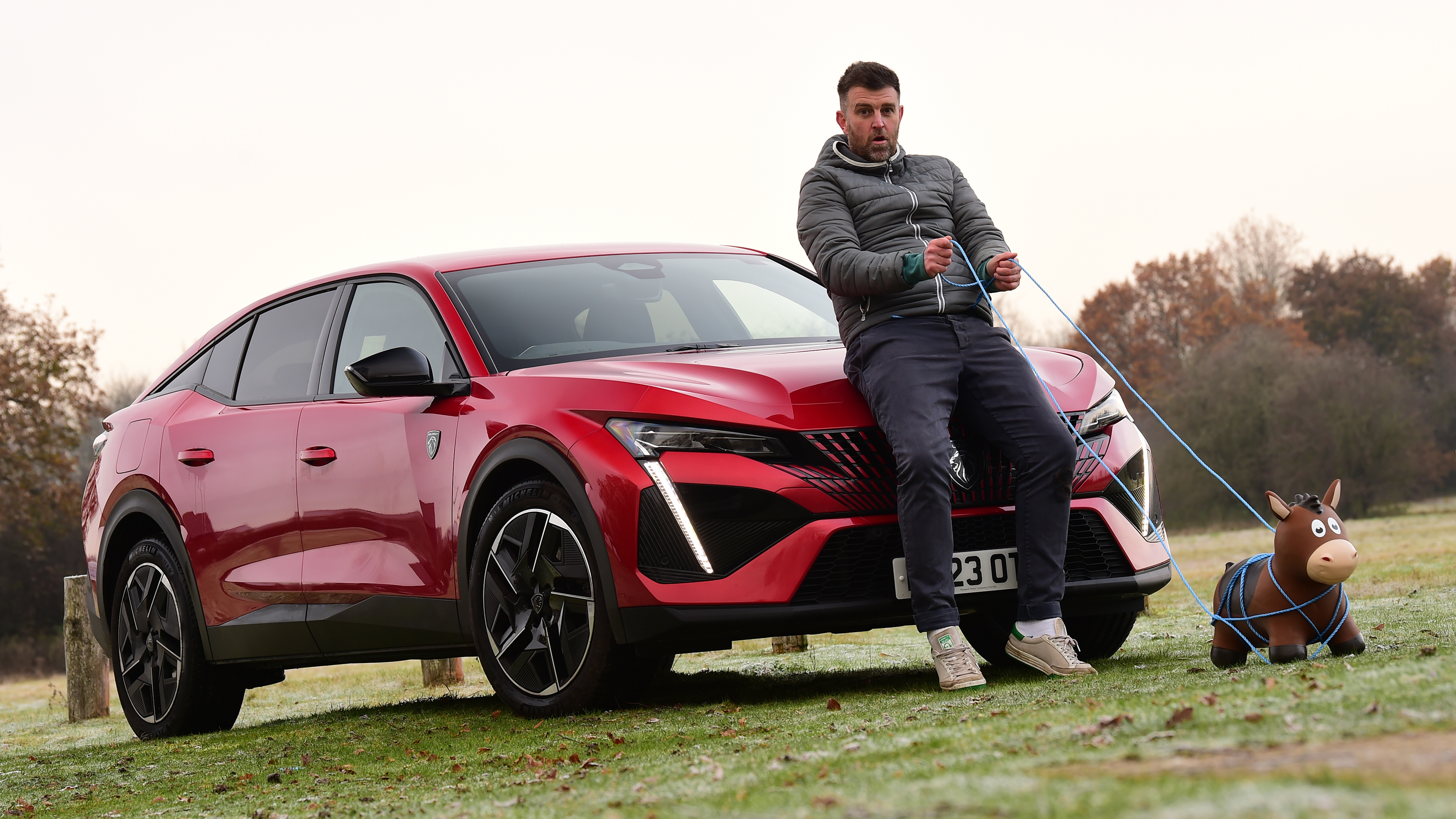 Auto Express head of digital content Steve Walker leaning on the Peugeot 408 GT while holding a toy horse