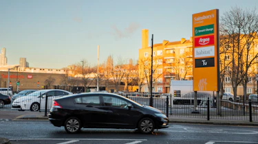 Honda Insight driving past Sainsburys supermarket