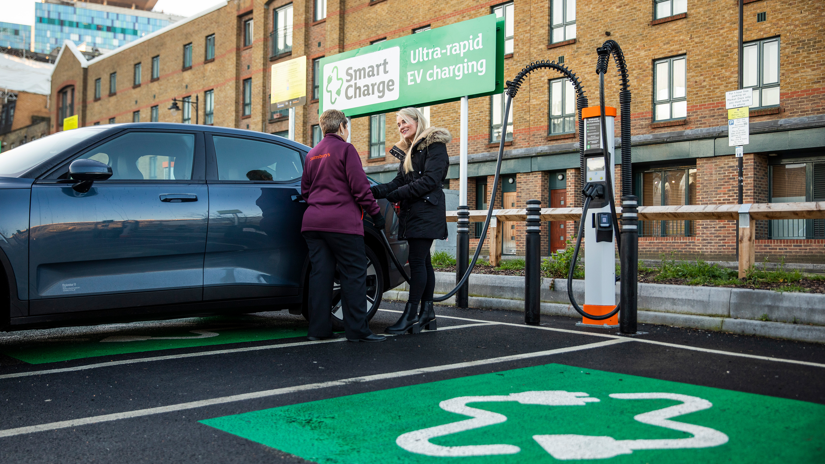 Sainsburys employee talking with customer next to EV charger