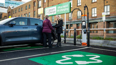 Sainsburys employee talking with customer next to EV charger