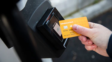 Person scanning credit card on Sainsburys EV charger contactless payment pad