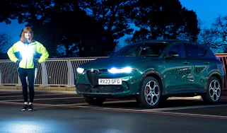 Auto Express pictures editor Dawn Grant standing next to the Alfa Romeo Tonale PHEV at night