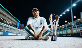 Lewis Hamilton sitting next to a trophy