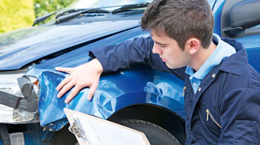 Technician inspecting a car's cosmetic damage
