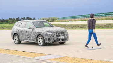BMW X3 prototype (camouflaged) driving towards a pedestrian crash test dummy
