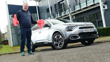 Auto Express executive editor Paul Adam standing next to the Citroen C4 X and wearing foam hands