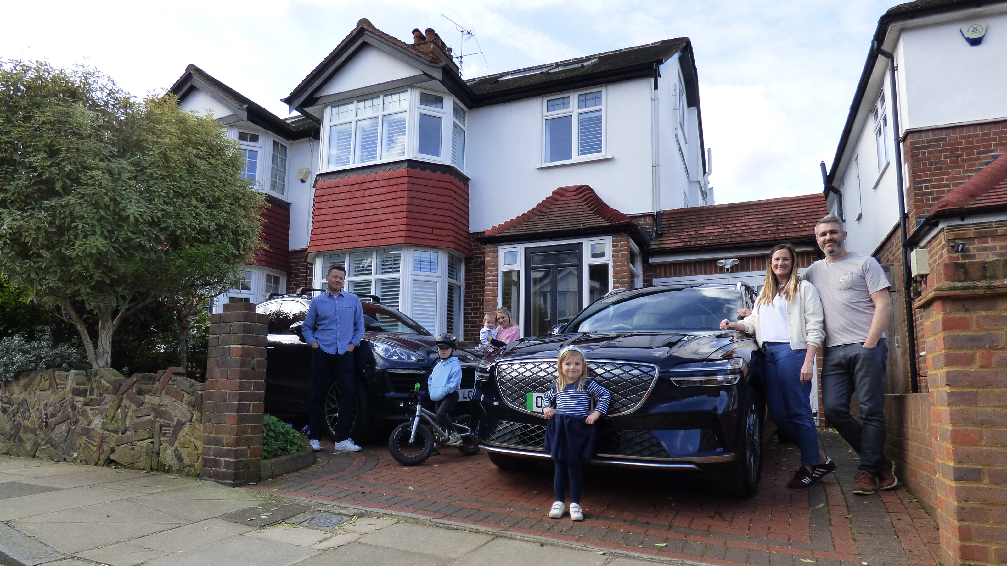 Auto express deputy editor Richard Ingram standing with the Genesis Electrified GV70 and Porsche Cayenne