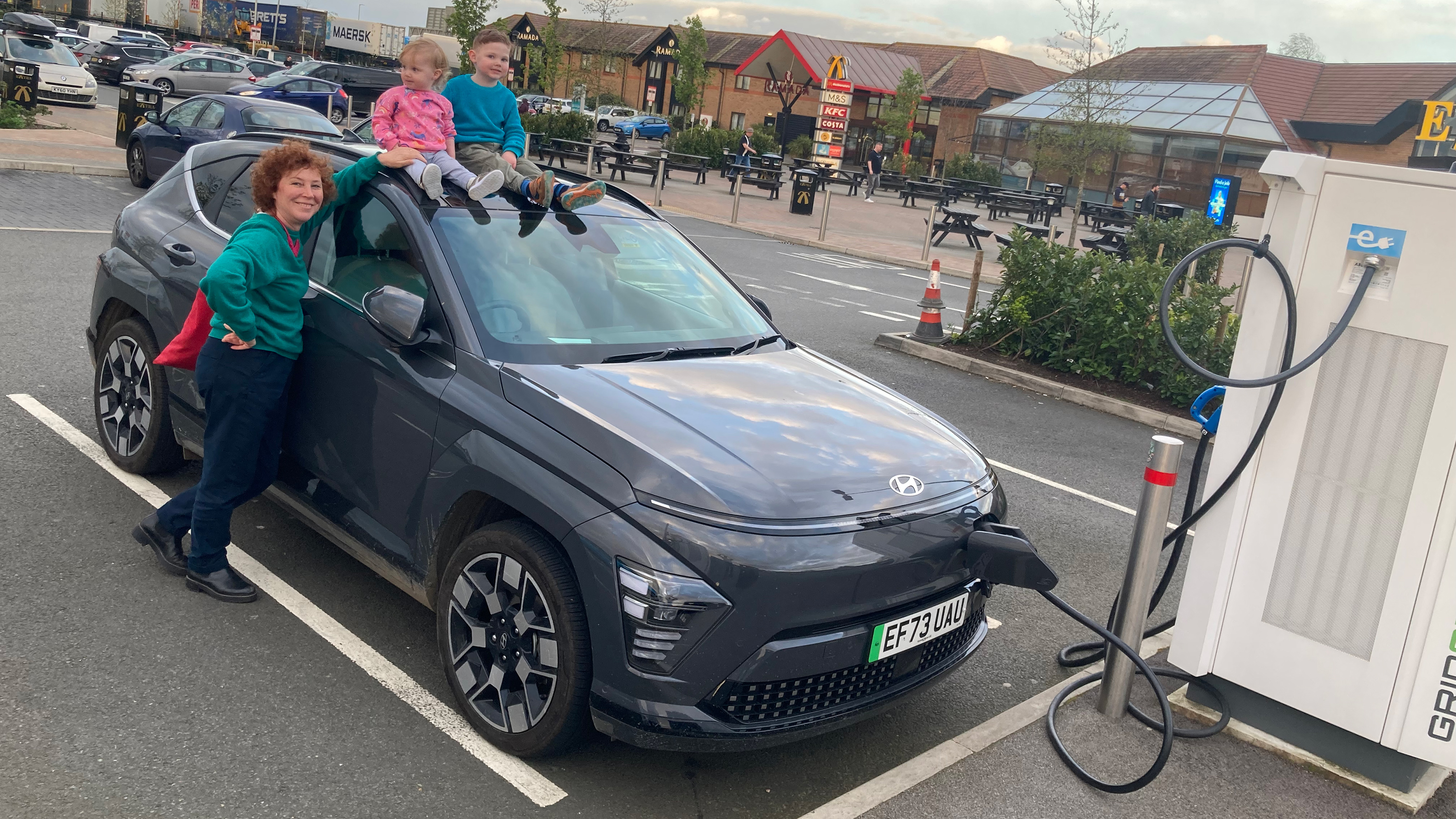 Auto Express creative director Darren Wilson's family standing with the Hyundai Kona while charging