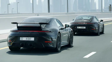 New Porsche 911's rear 3/4 driving down a road