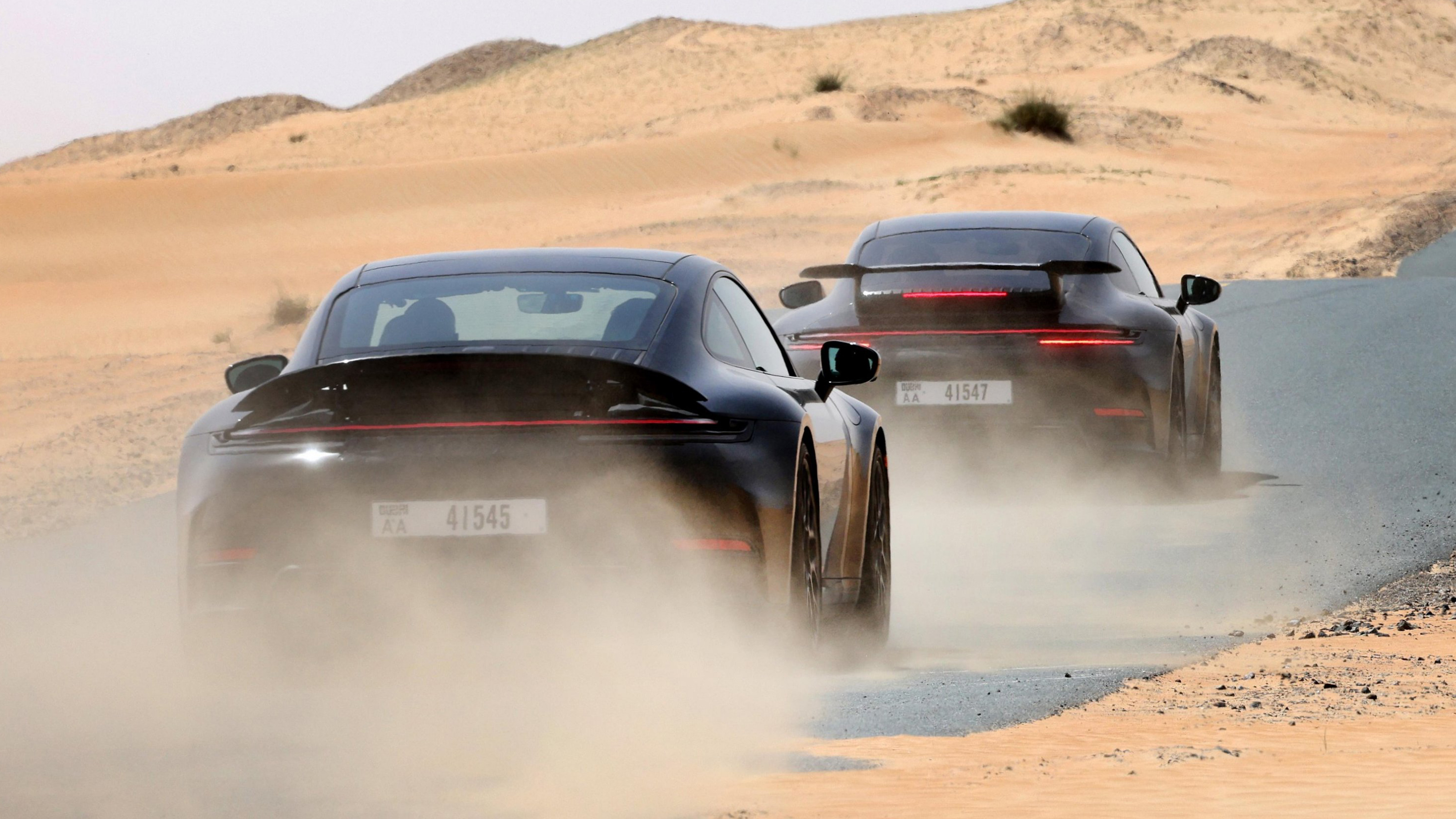 New Porsche 911's rear 3/4 driving down a desert road