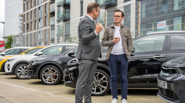 Tom Jervis discussing the rebrand next to a car lineup