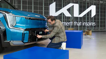 Tom Jervis sticking plate on the front of a KIA EV9