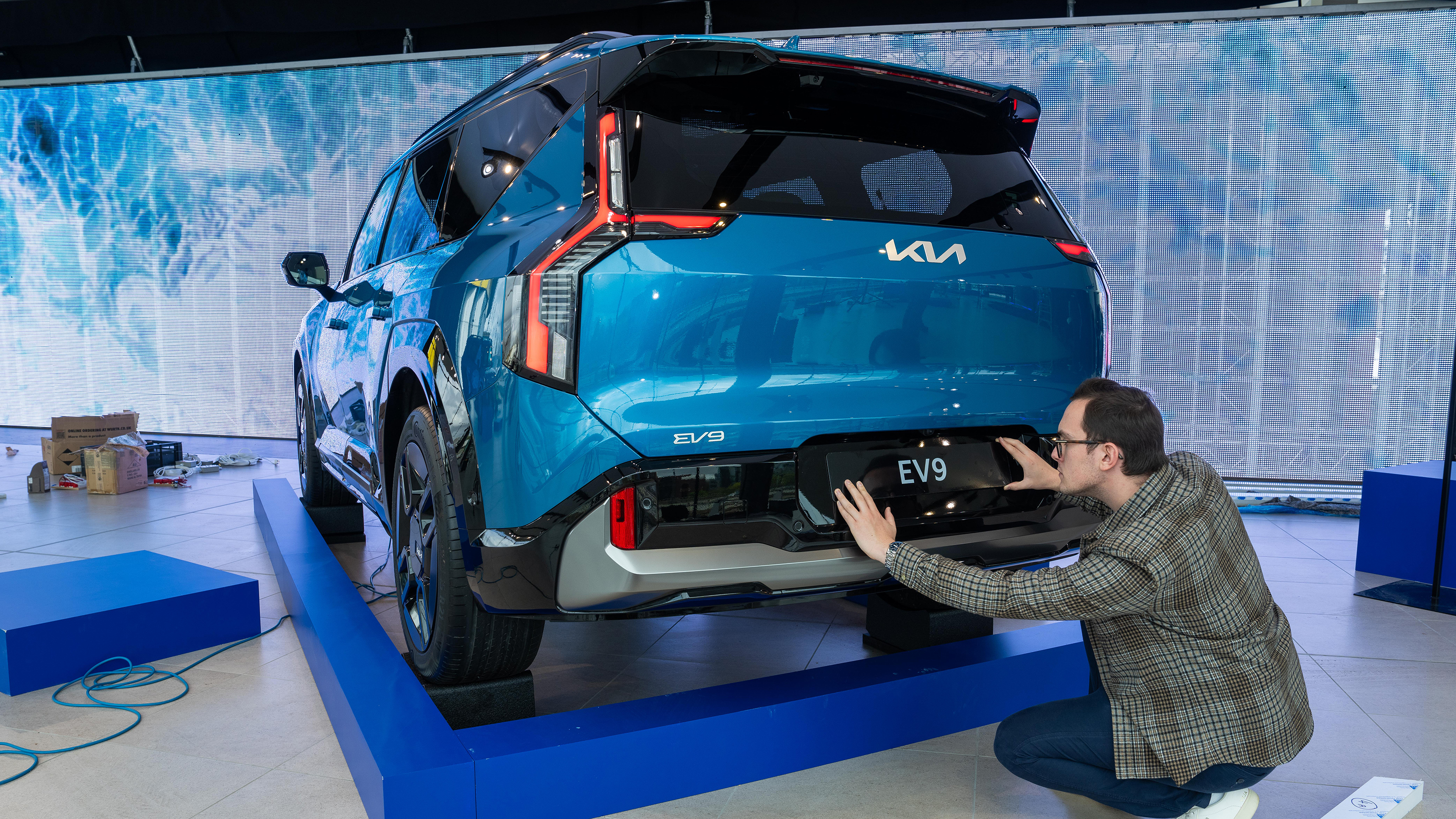 Tom Jervis sticking plate on the rear of a KIA EV9