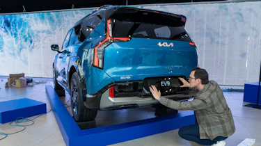 Tom Jervis sticking plate on the rear of a KIA EV9