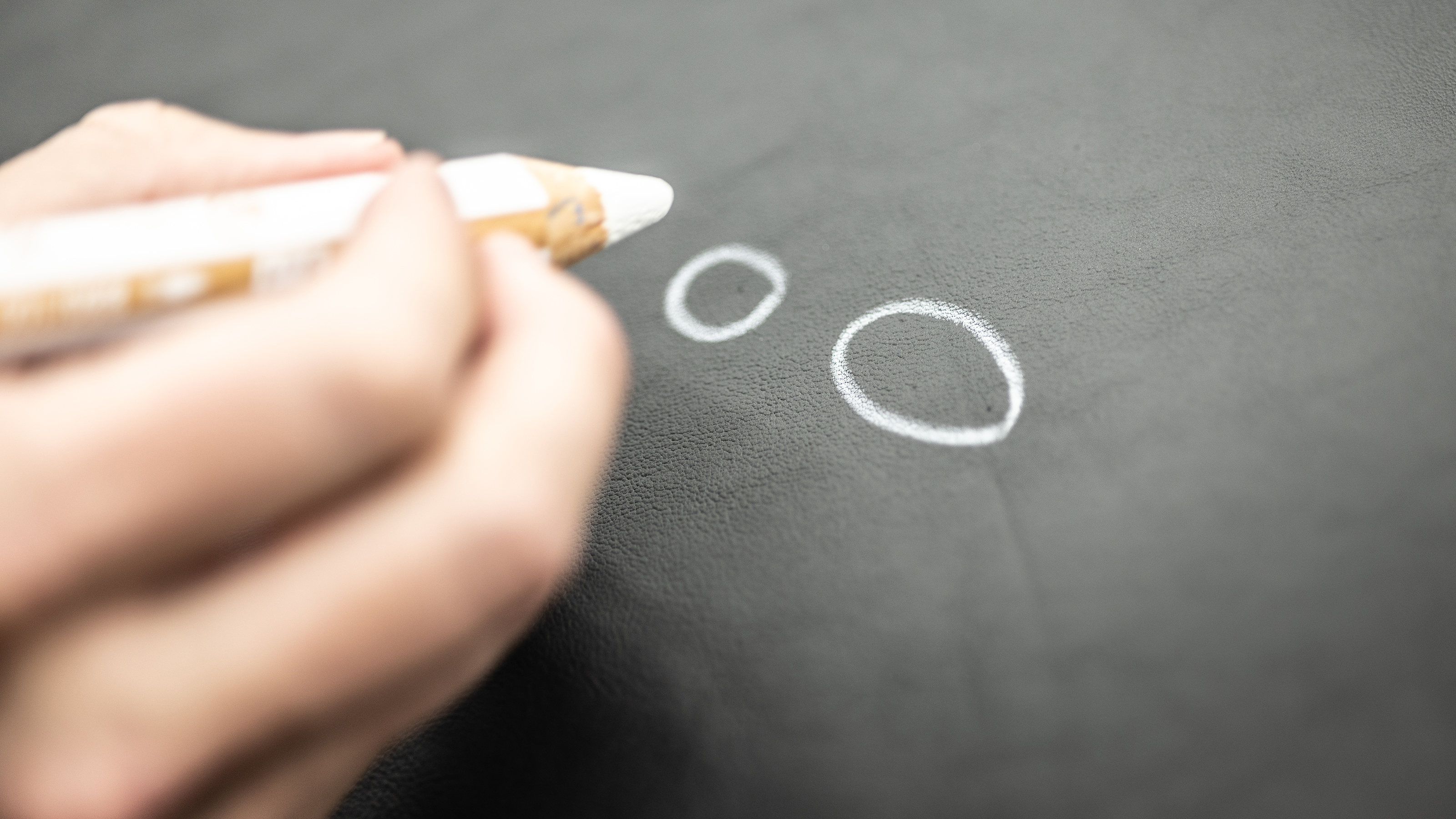 Person drawing circles on a piece of leather with a pencil