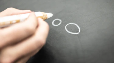 Person drawing circles on a piece of leather with a pencil