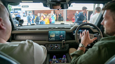 Auto Express news reporter Ellis Hyde and Shaun Birch sitting in the Auto Express news reporter Ellis Hyde standing with Land Rover Defender OCTA