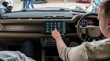 Auto Express news reporter Ellis Hyde operating the Land Rover Defender OCTA's infotainment sytem