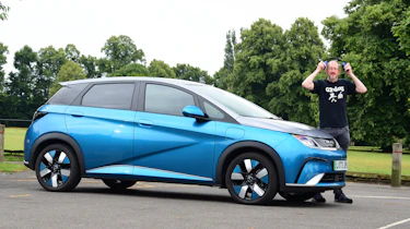 Auto Express chief sub-editor Andy Pringle standing next to the BYD Dolphin with a pair of ear protectors