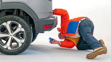 Dacia owner inspecting the Dacia Duster's rear bumper