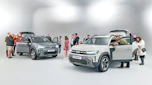 Group of Dacia Duster owners standing in a room with two brand-new Dacia Dusters