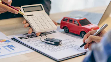 Finance contract, car key and calculator on desk