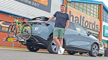 Auto Express head of digital content Steve Walker standing next to the Nissan Ariya outside a branch of Halfords
